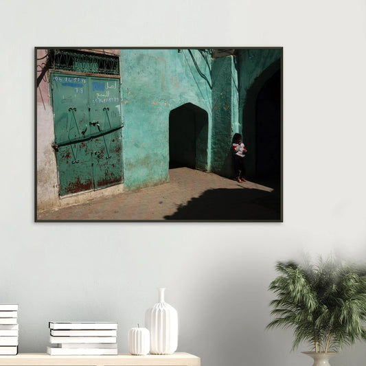 Candid fine art photograph titled 'Childhood in the Medina' featuring a young child standing in the shadows of a vibrant turquoise alley in Morocco - photography print by Paulo Côrte-Real